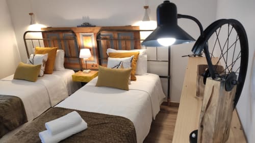 Quarto duplo da Kindnessmoon em Óbidos com camas brancas, almofadas mostarda, luminária pendente preta e decoração de bicicleta
