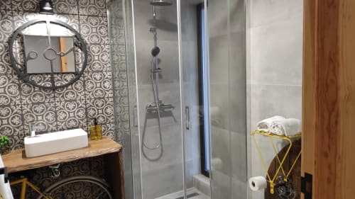 Banheiro moderno em boutique hotel português com azulejos estampados, cuba de apoio, box de vidro e toalheiro amarelo