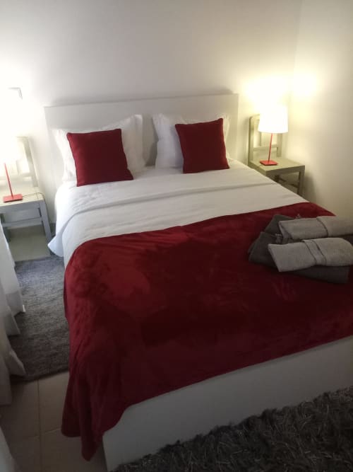 Quarto moderno com cama branca, almofadas e manta em bordô, luminárias de cabeceira e toalhas cinzentas na villa Kindnessmoon
