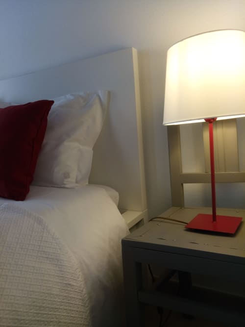 Quarto moderno na vila de Óbidos com roupa de cama branca, luminária vermelha no criado e vista da cidade