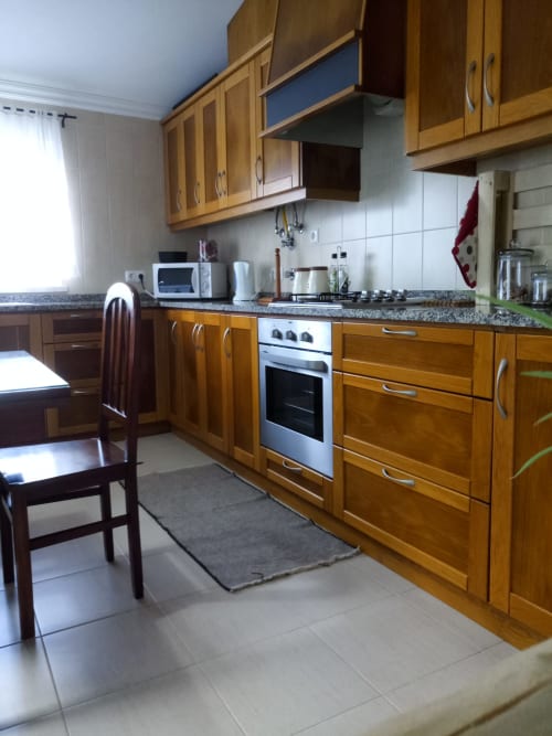 Cozinha espaçosa na villa Casa d'Amélia, Óbidos, com móveis de madeira, eletrodomésticos em aço inoxidável, bancadas em granito e