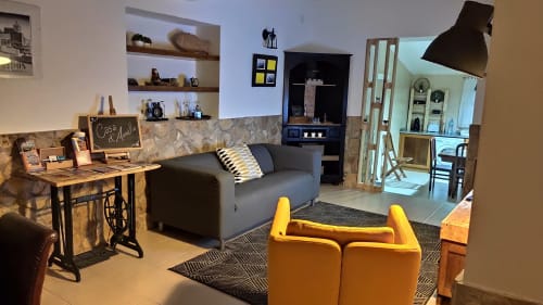 Sala de estar moderna da villa Kindnessmoon em Óbidos com sofá cinzento, cadeiras amarelas, escritório e prateleiras com vista para a cidade