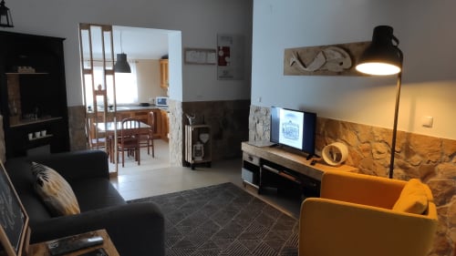 Sala de estar moderna na Villa Casa d'Amélia, Óbidos Portugal, com sofá preto, poltrona amarela, TV e luminária de piso preta