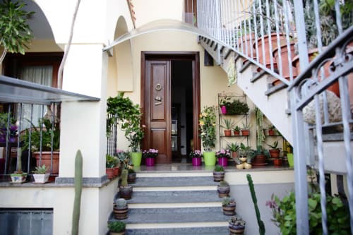Charming entrance to Affittacamere Al Mare with potted plants, wooden door, and staircase in Torre Grande Oristano
