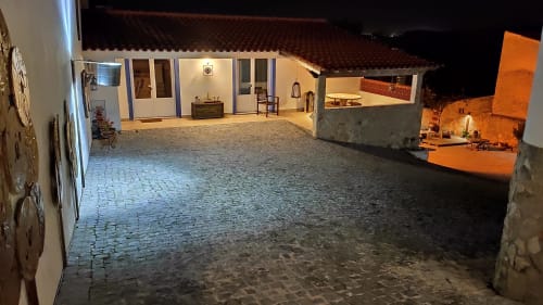 Nighttime courtyard of Casa d'Amélia villa in Óbidos, Portugal with lit buildings, paved grounds and grill area