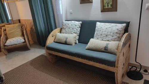Wooden sofa with teal cushions and patterned pillows in Casa d'Amélia villa sitting area at Kindnessmoon, Óbidos Portugal