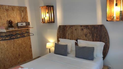 Bedroom at Kindnessmoon in Obidos with wooden headboard, white bedding, gray pillows, and warm lighting.