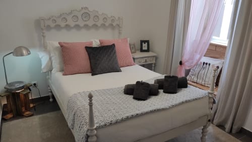 Quarto elegantemente decorado na villa Kindnessmoon em Óbidos com cama de ferro branco, almofadas rosa e vista da cidade