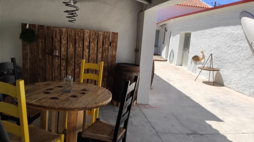 Mesa de jantar rústica em madeira com cadeiras amarelas no pátio de moradia em Óbidos, Portugal