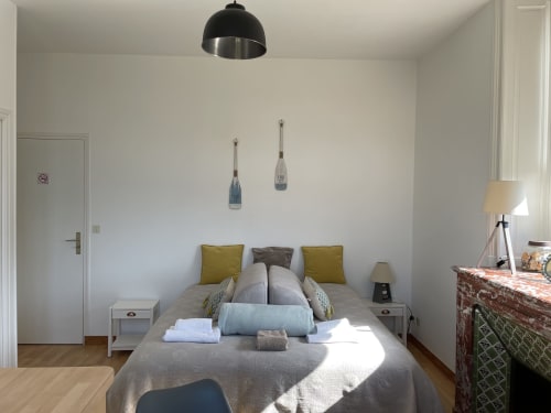 Chambre moderne à la Résidence Le Roc Fleuri à Saint Malo avec lits jumeaux, coussins olive, luminaires suspendus et lumière naturelle