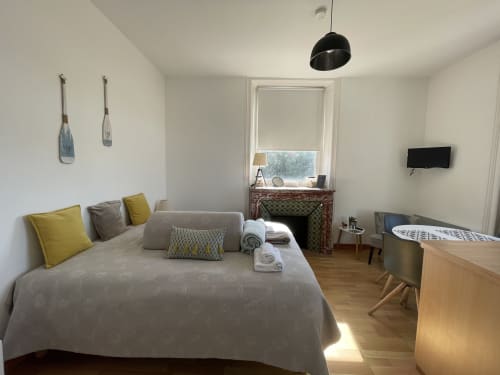 Chambre lumineuse à la Résidence Le Roc Fleuri à Saint-Malo avec lit, TV, cheminée et vue sur le jardin