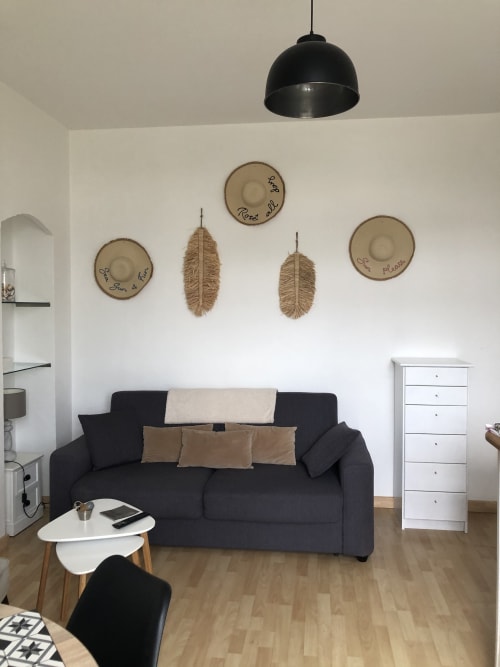 Salon moderne de la Résidence Le Roc Fleuri à Saint-Malo avec canapé noir, lampe suspendue et mur décoratif