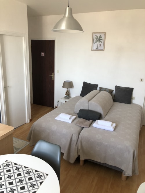 Chambre spacieuse à la Résidence Le Roc Fleuri, Saint Malo avec lits beige, luminaires suspendus et mobilier moderne