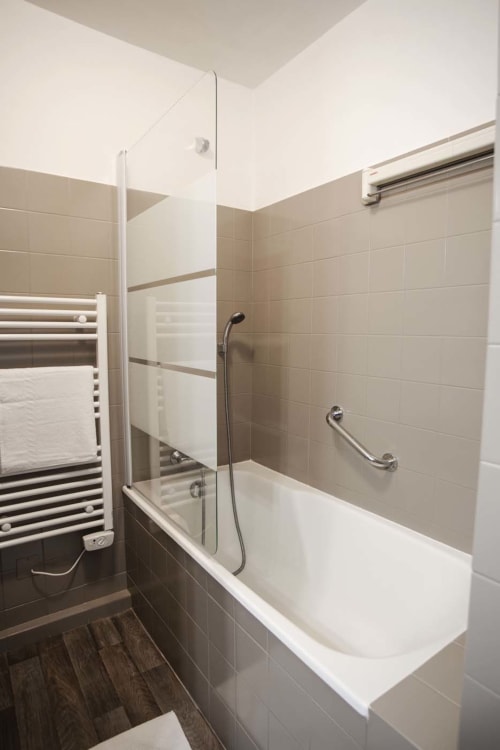 Salle de bain moderne avec baignoire, douche vitrée et sèche-serviettes chauffant à la Résidence Le Roc Fleuri, Saint Malo