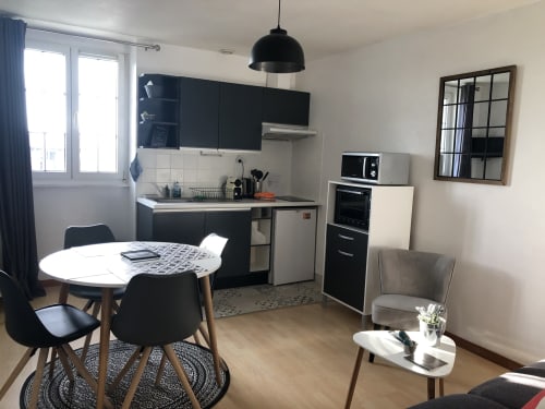Cuisine-séjour contemporain à la Résidence Le Roc Fleuri, appartement à Saint-Malo avec table à manger, mobilier noir et inox