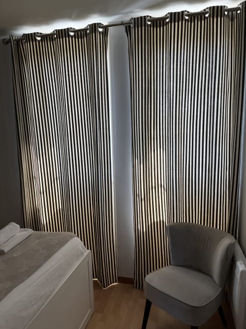 Chambre moderne à la Résidence Le Roc Fleuri avec rideaux rayés, lit et fauteuil à Saint-Malo