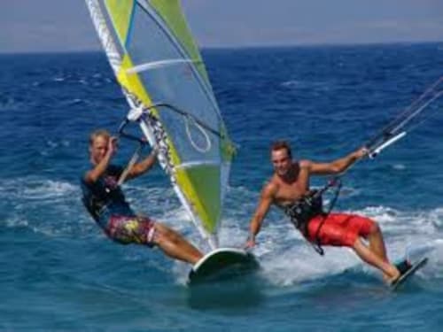 Due windsurfisti cavalcano le onde sulla spiaggia Torre Grande vicino ad Affittacamere Al Mare a Oristano, Italia