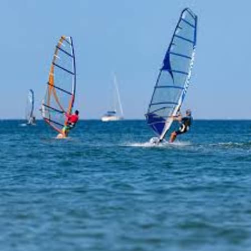 Windsurfisti con vele colorate sulle acque turchesi vicino a Torre Grande Oristano, Italia