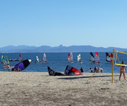 Spiaggia di kitesurf a Torre Grande Oristano con aquiloni colorati, lido sabbioso e sfondo montano