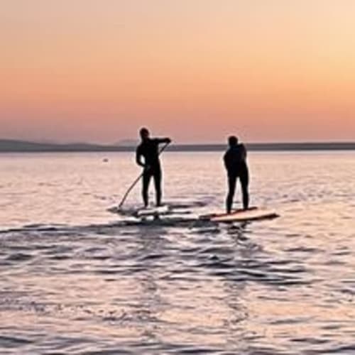 Due appassionati di paddleboard al tramonto vicino a Torre Grande Oristano, perfetto per sport acquatici presso Affittacamere Al Mare