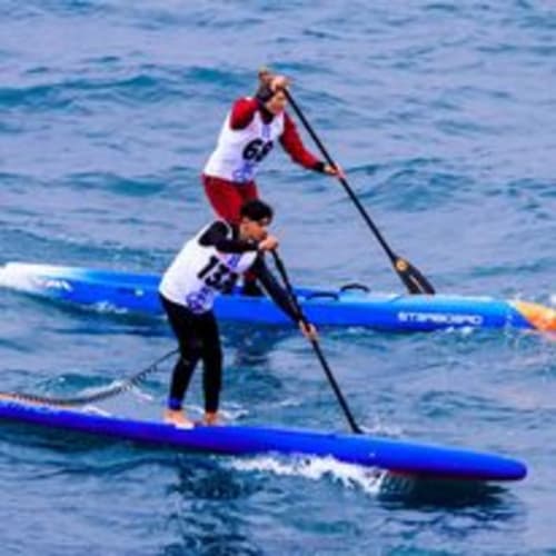 Gareggini di stand-up paddle su tavole blu nelle acque turchesi vicino a Torre Grande Oristano