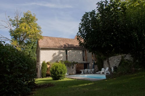 Chambres d'hôtes Les Pratges à Figeac : maison en pierre avec piscine, pelouse et arbres