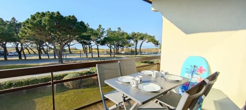 Coin repas sur la terrasse de l'appartement Mer et Maisons à La Trinité sur Mer avec vue mer, table, chaises et paysage côtier.