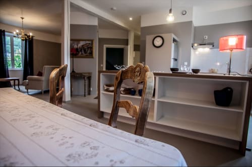 Espace petit-déjeuner moderne aux Chambres d'hôtes Les Pratges à Figeac avec table de repas, chaises et plan de travail de cuisine