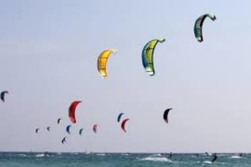 Numerosi aquiloni colorati volano sopra le acque blu dell'oceano vicino a Torre Grande Oristano