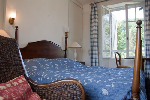 Chambre douillette aux Pratges B&B à Figeac avec lit à baldaquin en bois et vue sur le jardin