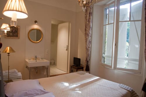 Chambre élégante aux Chambres d'hôtes Les Pratges à Figeac avec salle de bain privée, lit et portes-fenêtres