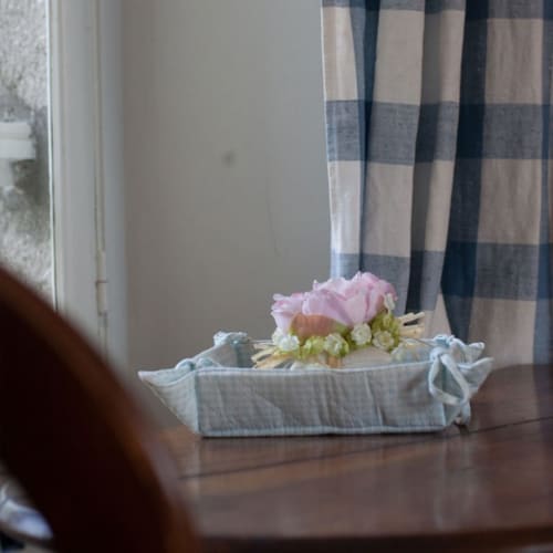 Composition florale aux roses roses et fleurs blanches dans un panier en lin bleu aux Chambres d'hôtes Les Pratges, Figeac