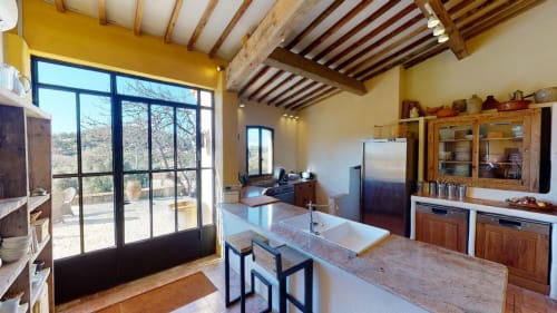 Cuisine du gîte Saint Martin à Ollioules avec poutres apparentes, îlot central, meubles bois et vue sur la terrasse