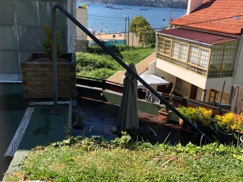 Terraza de Casa Arealonga con vistas al mar sobre la ría de Vigo, con tarima de madera, sombrilla negra y edificios costeros