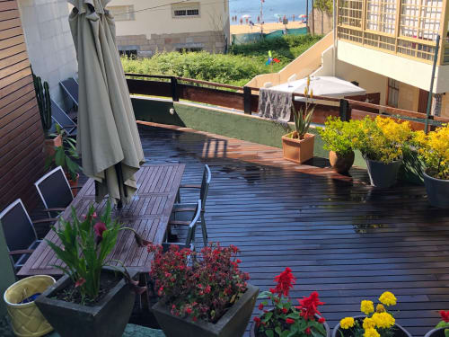 Terraza en la azotea de Casa Arealonga en Vigo con tarima de madera, macetas con flores, tumbonas y vistas al océano