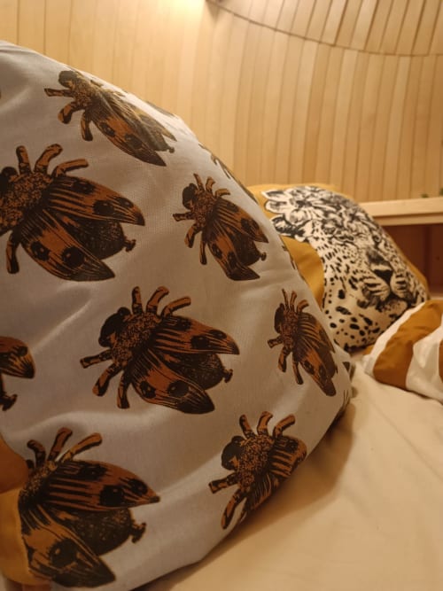 Decorative pillows with insect prints on bed at Les Refuges Du Chalet cottage in Jalhay, Belgium