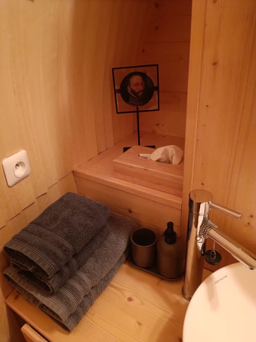 Compact wooden bathroom at Casa LeopArt cottage with sink, mirror portrait, towels, and modern fixtures