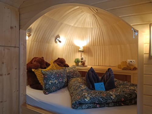 Gemütliches Holz-Pod-Schlafzimmer im Les Refuges Du Chalet in Jalhay mit Kissen, gemusterter Bettwäsche und warmem Licht