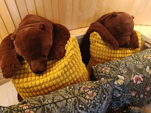 Zwei braune Plüschbären mit gelben Maiskolben auf einem Blumenmusterbett im Chalet Les Refuges