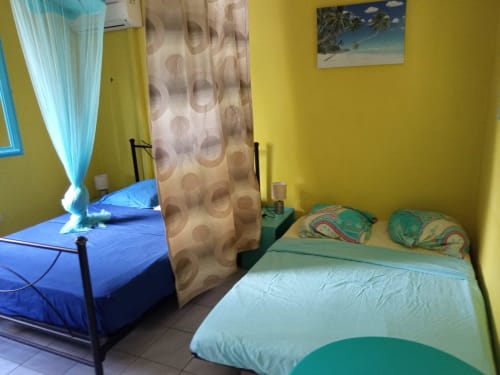 Chambre jaune éclatante au Caribgites BnB à Sainte-Anne avec deux lits, climatisation et décoration tropicale