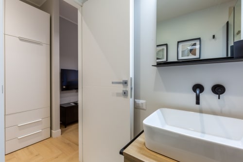Bagno moderno presso CASA LOUNGE ISTRIA con lavabo bianco, rubinetteria nera e pavimentazione in legno