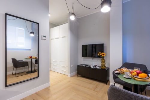 Camera moderna a Casa Lounge Istria a Cagliari con TV a parete, zona pranzo e parete con specchi