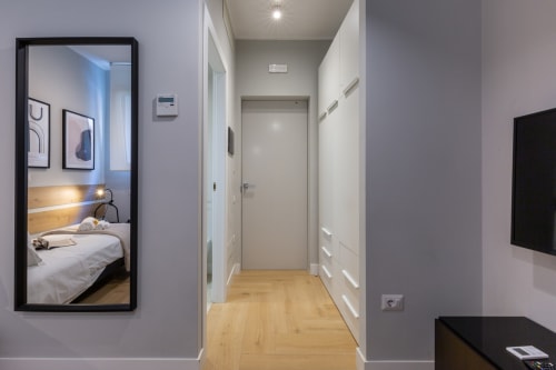 Corridoio moderno della camera CASA LOUNGE ISTRIA dell'hotel Cagliari con pavimento in legno, arredamenti bianchi e specchio della camera da letto