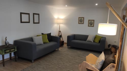 Modern living room with two dark gray sofas, green accent pillows, wood staircase, and framed artwork in Obidos cottage