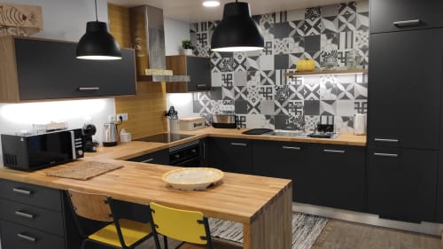 Modern black kitchen with wood island, patterned backsplash, dining area with yellow chairs, Kindnessmoon BnB cottage in