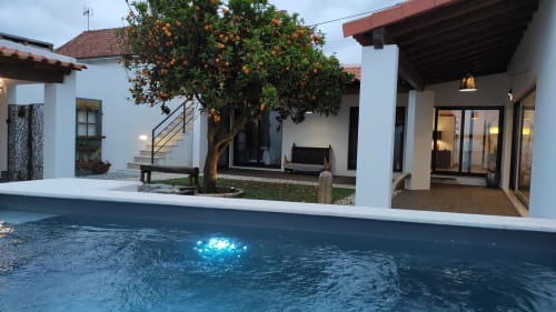 Piscina da Kindnessmoon cottage em Óbidos, Portugal, com laranjeira e edifícios brancos ao entardecer