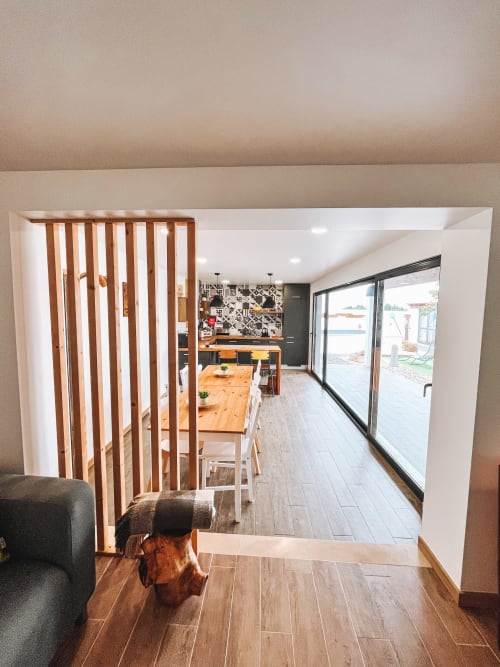 Modern open-plan cottage in Óbidos with wooden divider, dining area, and sliding glass doors to balcony