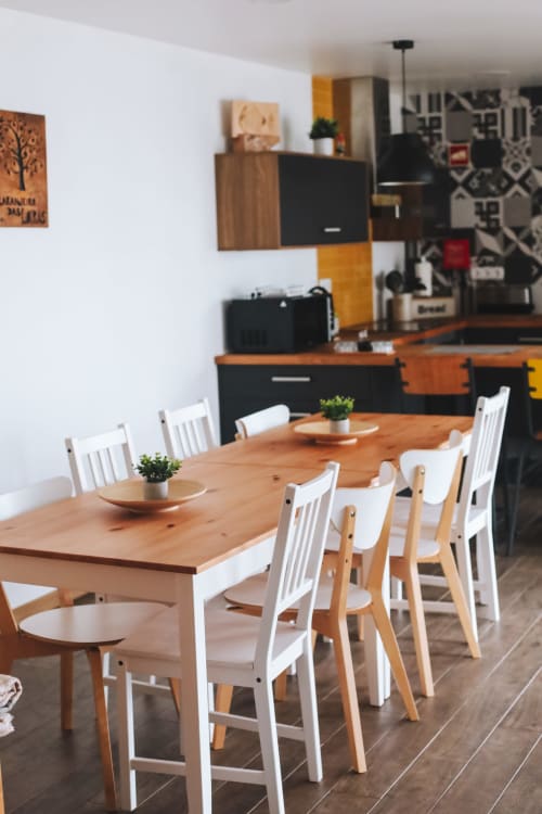 Modern dining area with wooden table, white chairs, and kitchenette in Obidos cottage rental