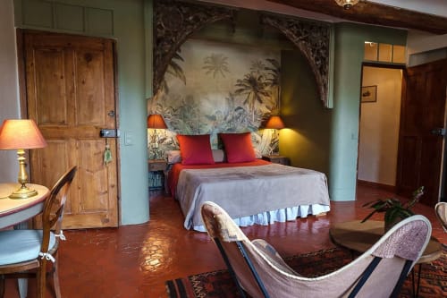 Jade Suite Schlafzimmer im La Bouscatière in Moustiers-Sainte-Marie mit tropischer Kunst, roten Kissen und Flussblick