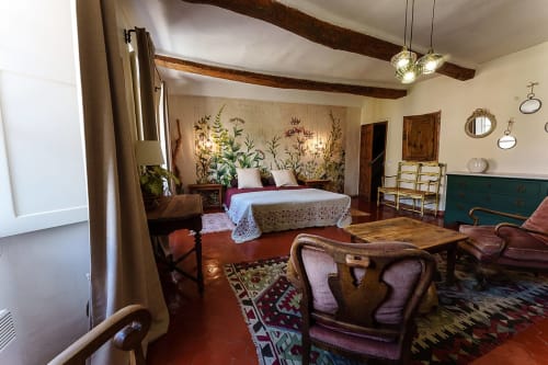 Ambre Suite Schlafzimmer im La Bouscatière in Moustiers-Sainte-Marie mit Bett, rustikalen Balken, botanischer Tapete und Loungebereich